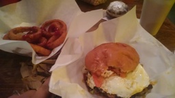 bacon cheese burger with an egg and grilled onions